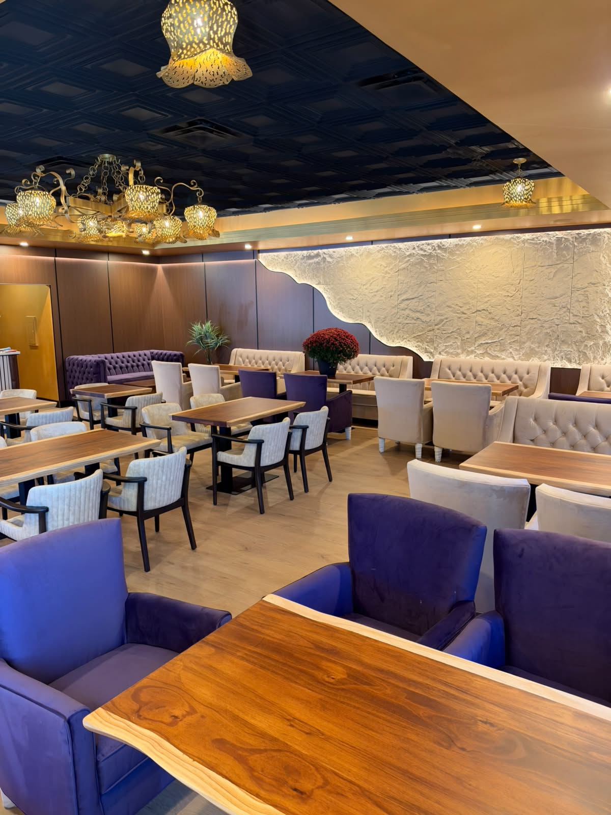 A view across the lounge with cream seating, wood tables and warm gold lighting